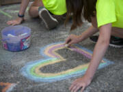 Alexandra Lafayette of Vancouver, member of The Joy Team, draws a heart during The Joy Team’s annual Chalk the Walks in 2016. This year’s event is on Tuesday.