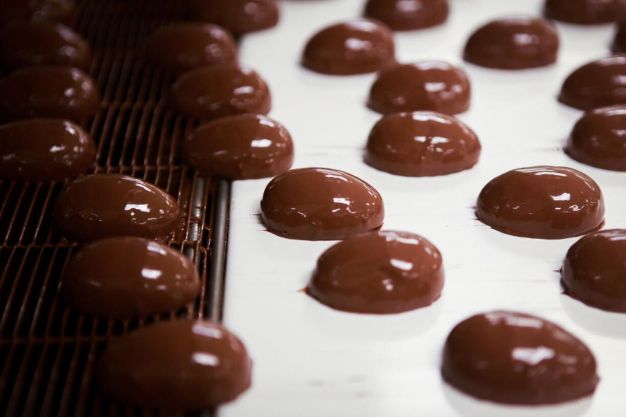 Chocolate-covered marshmallows travel down an enrobing belt before being dunked under a curtain of chocolate for a second time at See’s Candies in Los Angeles.