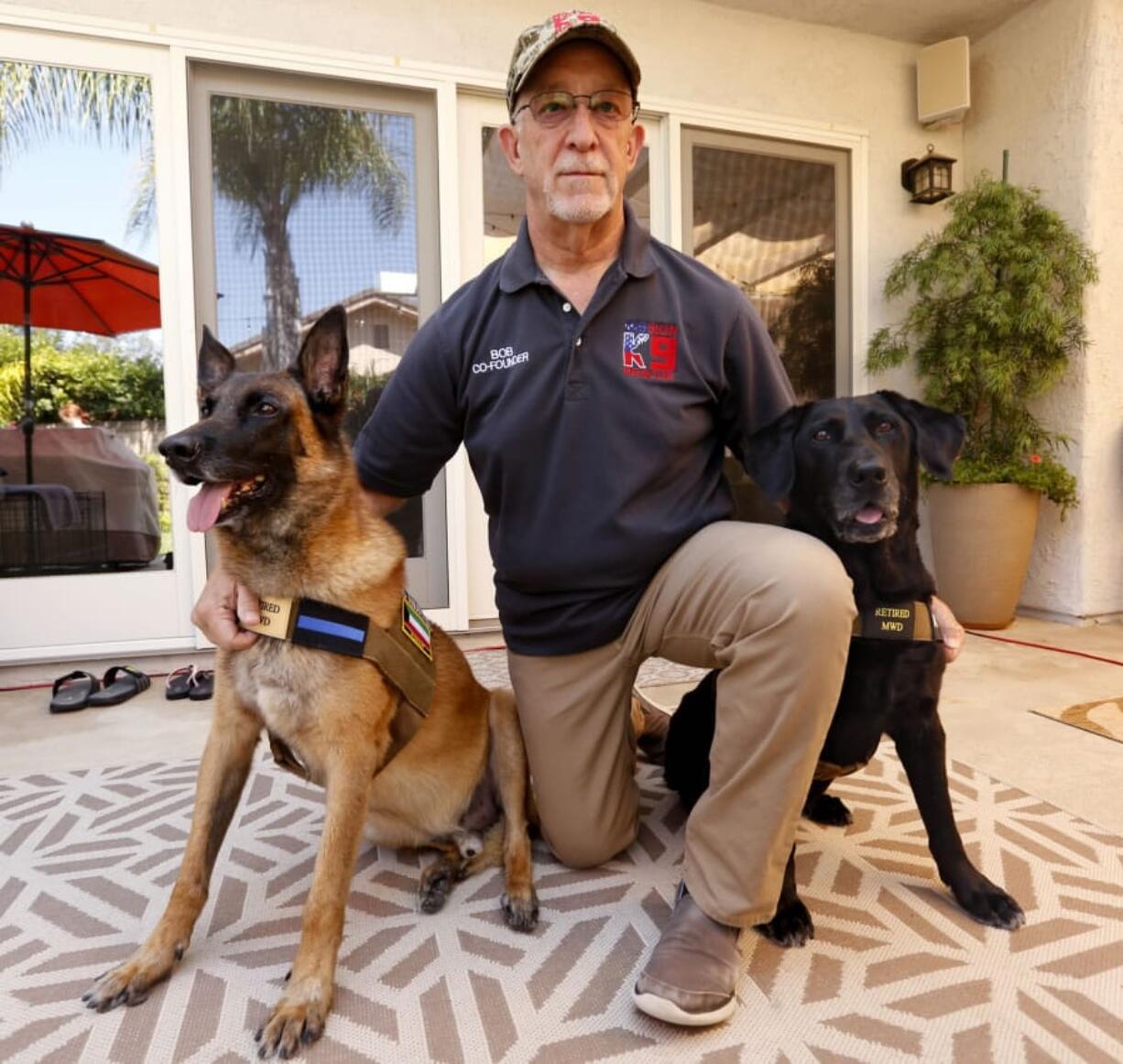 Mission K9 Rescue co-founder Bob Bryant kneels next to Oreo, right, a military working dog and Anubis, a contract working dog, at his home in Newbury Park.