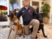 Mission K9 Rescue co-founder Bob Bryant kneels next to Oreo, right, a military working dog and Anubis, a contract working dog, at his home in Newbury Park.