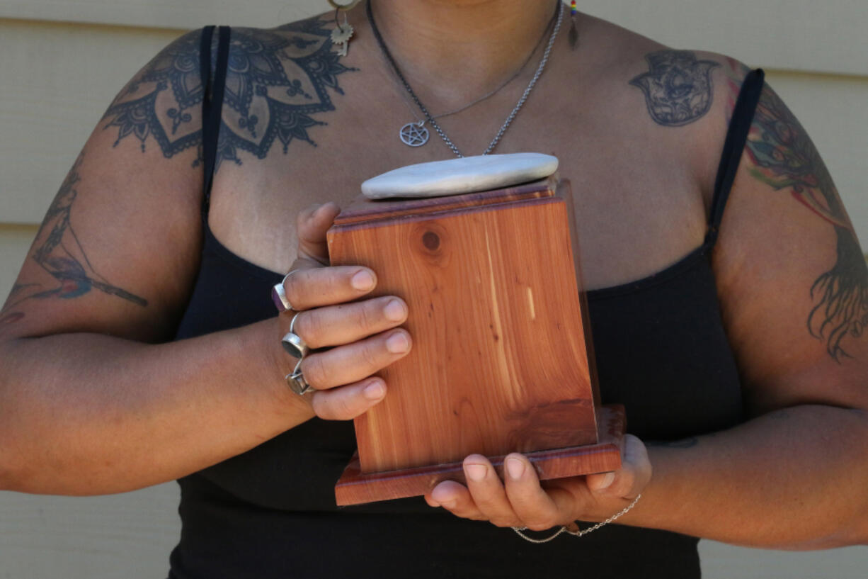 Lashanna Williams holds the remains of Prince Charming, her beloved 110-pound Lab-Shepherd mix. Prince Charming’s remains were placed in this box after being returned from Resting Waters. Atop the box is her pet’s paw print.