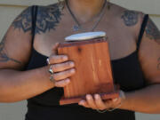 Lashanna Williams holds the remains of Prince Charming, her beloved 110-pound Lab-Shepherd mix. Prince Charming’s remains were placed in this box after being returned from Resting Waters. Atop the box is her pet’s paw print.