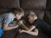 Tristin Fuller, left, and his twin brother, Justin, both 11, spend a few moments bonding with their 8-week-old puppy, Kona,at their La Center home Tuesday morning. The boys are among the 3,200 children who have been cared for in the NICU at Legacy Salmon Creek Medical Center since its opening in 2005.