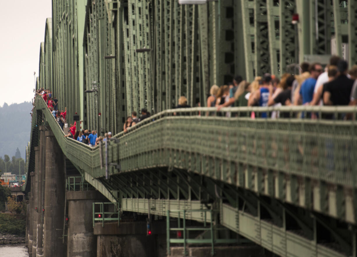 Hundreds gather on the pedestrian sidewalk of the Interstate 5 Bridge on Monday to join hands and say the Serenity Prayer in celebration of their recovery from addiction.