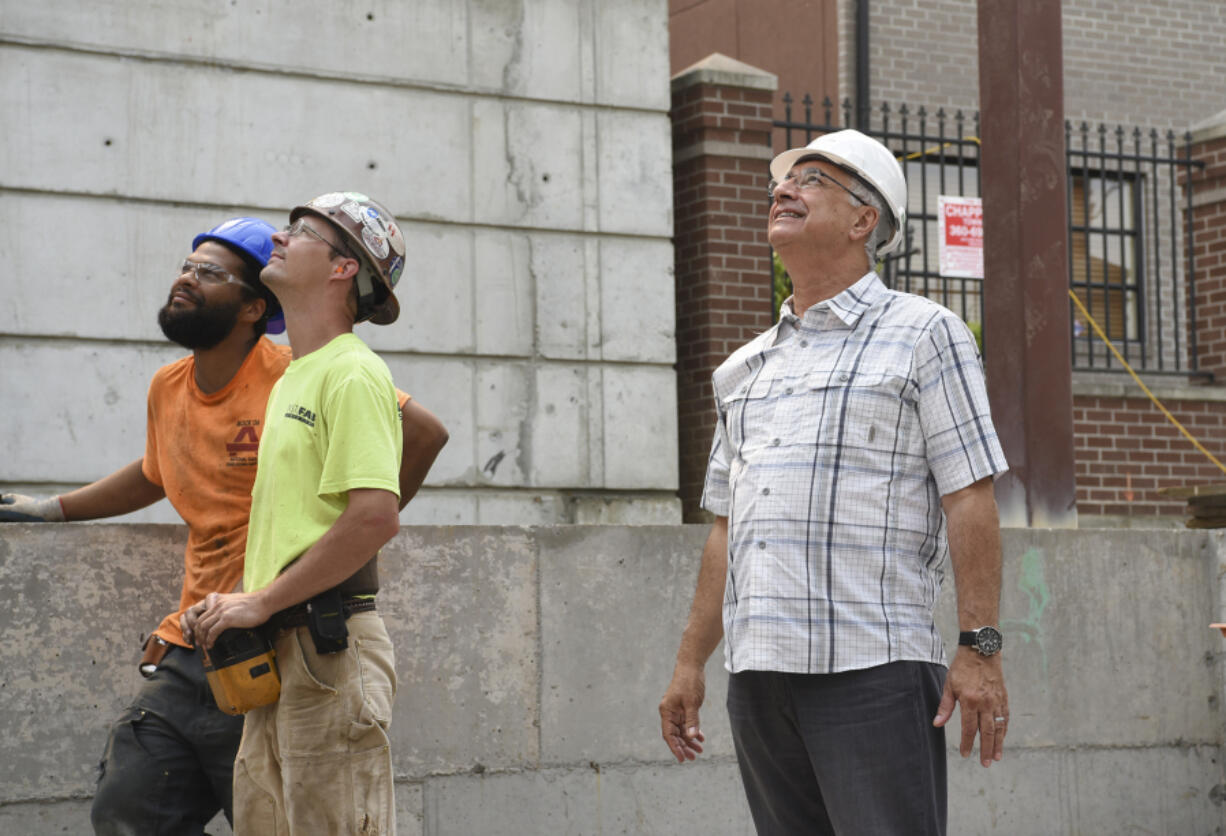 Instafab employees Pacino Palmore, from left, and Todd Steward look up at a crane moving a beam with Elie Kassab, president and owner of Prestige development, on Sept. 5 at the construction site for Our Heroes Place, a multifamily complex on East Mill Plain Boulevard in Vancouver.