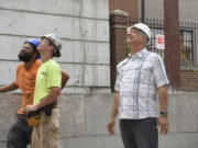 Instafab employees Pacino Palmore, from left, and Todd Steward look up at a crane moving a beam with Elie Kassab, president and owner of Prestige development, on Sept. 5 at the construction site for Our Heroes Place, a multifamily complex on East Mill Plain Boulevard in Vancouver.