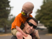 Declan Reagan, 5, sits atop the shoulders of his father, Francis Reagan, Tuesday outside the Washougal Police Department, where his dad serves as a police officer. Declan received a bone marrow transplant in July after being diagnosed with two types of cancer. “A woman in another country gave him the chance to have a life, and that’s really cool” says his mother, Lauren Reagan.