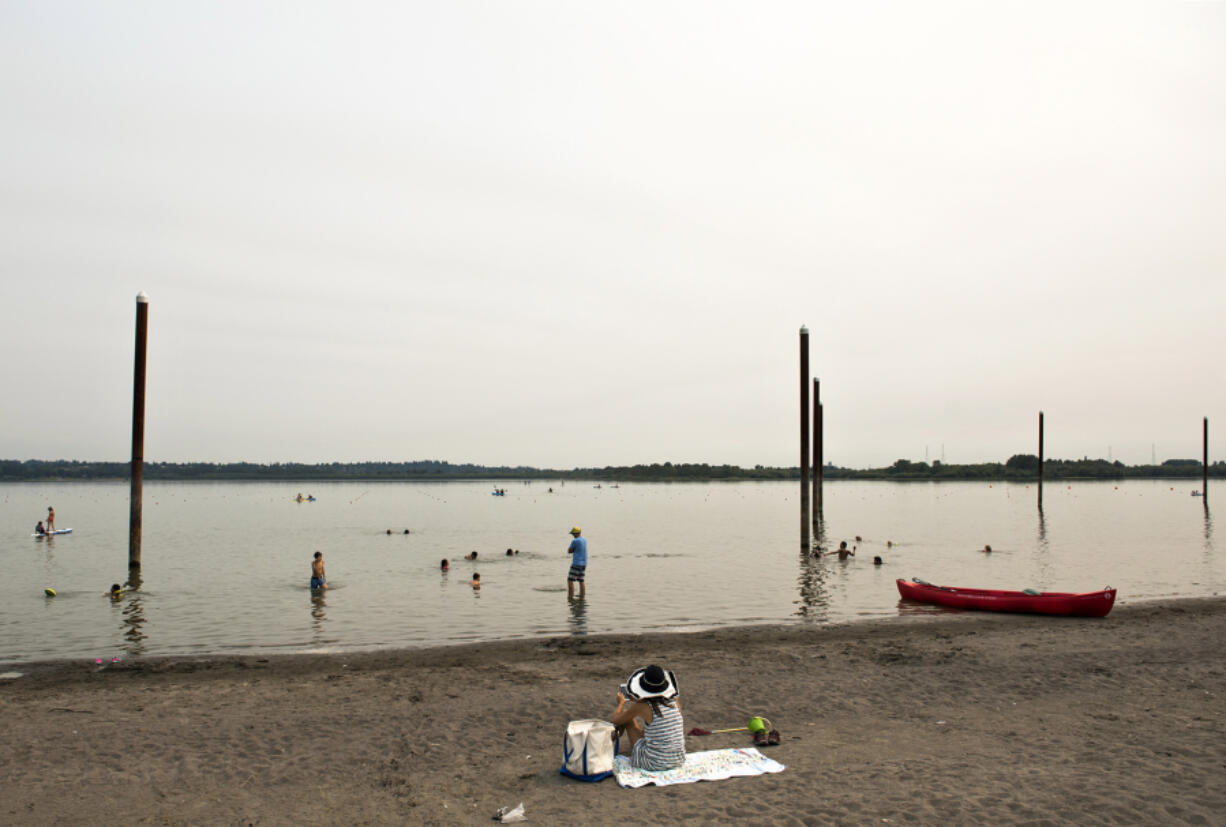 A smokey haze falls over Vancouver Lake as people enjoy the sandy beach and cool water on Monday, Sept. 4, 2017.