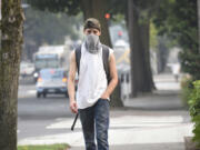 Alexander Fuller of Vancouver walks down Main Street in Vancouver on Tuesday wearing a face mask to protect himself from smoke and ash in the air caused by the Eagle Creek Fire in the Columbia River Gorge.
