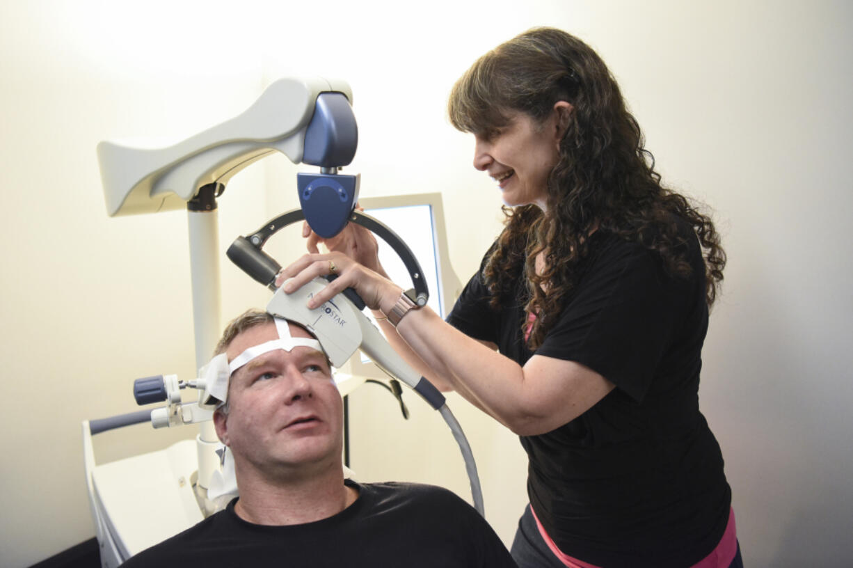 Todd Walker, 46, left, holds his head still while psychiatric nurse practitioner Ruth Rogers prepares a NeuroStar machine for transcranial magnetic stimulation Sept. 6 at Serenity TMS in Vancouver. TMS is a Food and Drug Administration-approved treatment for major depressive disorder.