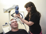 Todd Walker, 46, left, holds his head still while psychiatric nurse practitioner Ruth Rogers prepares a NeuroStar machine for transcranial magnetic stimulation Sept. 6 at Serenity TMS in Vancouver. TMS is a Food and Drug Administration-approved treatment for major depressive disorder.