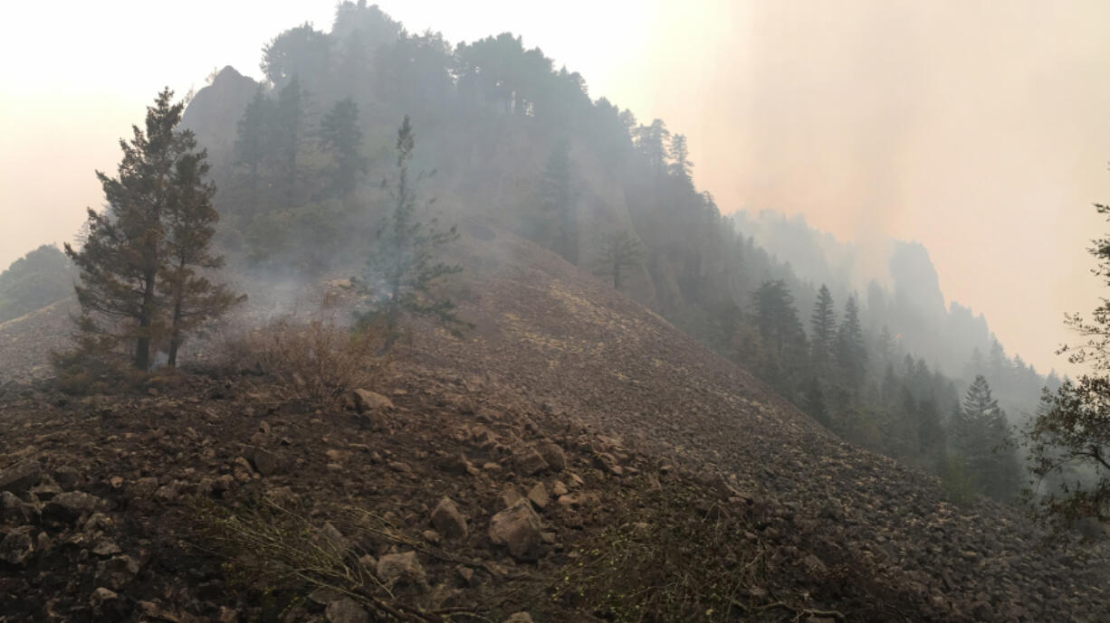 A burned area smolders on Archer Mountain in western Skamania County on Wednesday morning as the fire continues to burn in the background. State fire officials said the fire had grown from 25 to 75 acres as of Wednesday.