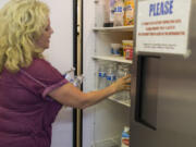 Office manager Sherri Owens restocks Bethel Community Church’s refrigerator with water bottles. “We have a really good church family that’s willing to step up and help,” she said.