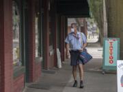 Letter carrier Curt Waser protects himself from wildfire smoke with a mask issued by the postal service as he walks his route through Uptown Village on Wednesday morning, Sept. 6, 2017.