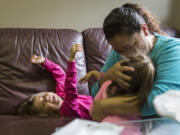 Vanessa Estrada kisses her daughter, Alayna, 3, while her other daughter Aaliyah, 4, plays on the couch at Open House Ministries. “I just want to be happy with my children,” Vanessa Estrada said.