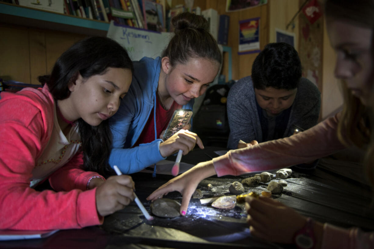 Wy’east Middle School sixth-graders Liz Rangel, from left, Grace Smith, Diego Ku Bauzo and Audrey Shillinger dust off fossils during Evergreen Public Schools’ dual immersion class on Tuesday morning. The students have been in the same class, where they are instructed in both Spanish and English, since 2011 when they entered kindergarten. “We’re like family,” Grace said.