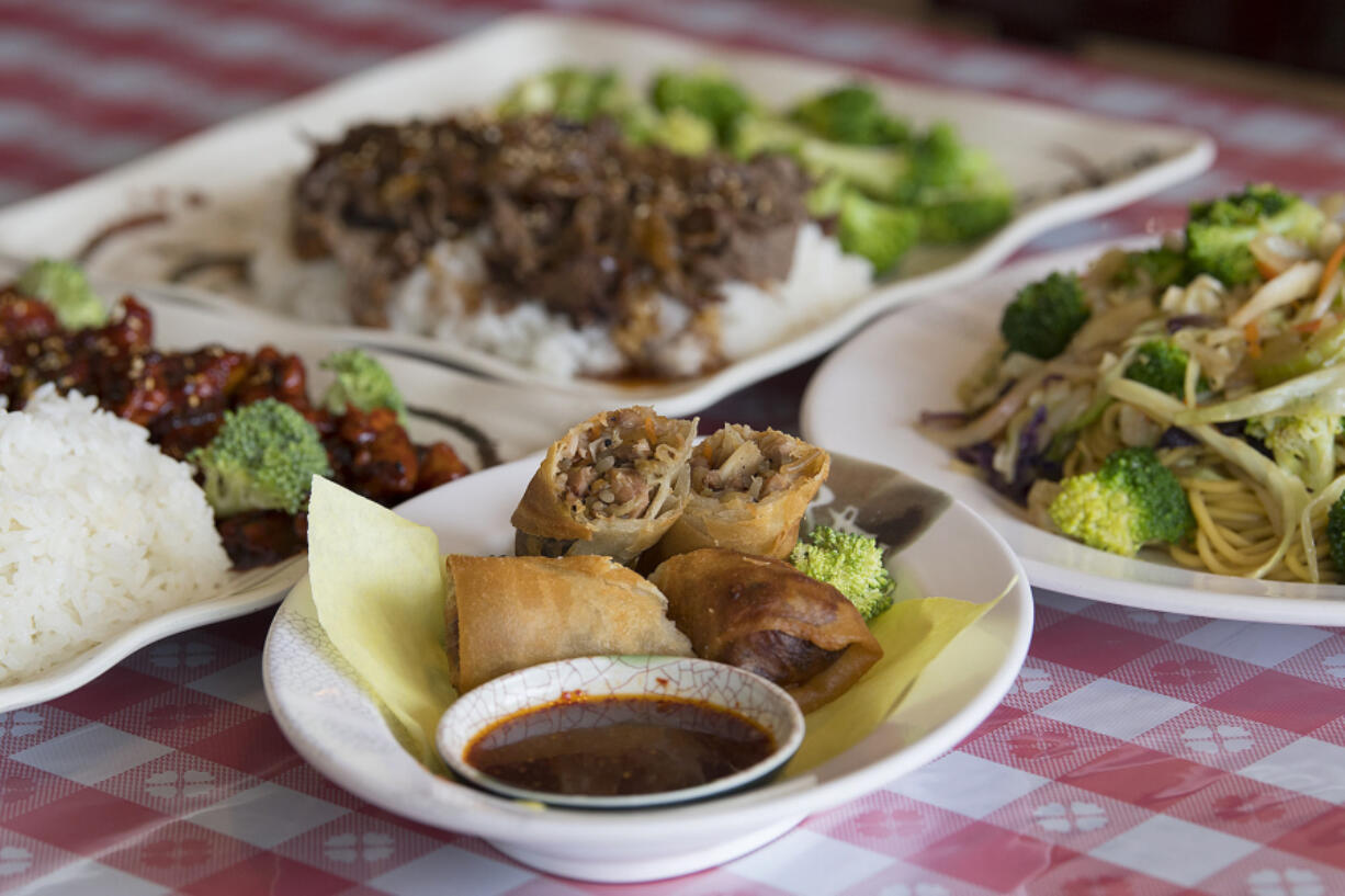 Spring rolls, center, served with spicy chicken, clockwise from left, beef broccoli and vegetable yakisoba at Du’s Teriyaki in central Vancouver.