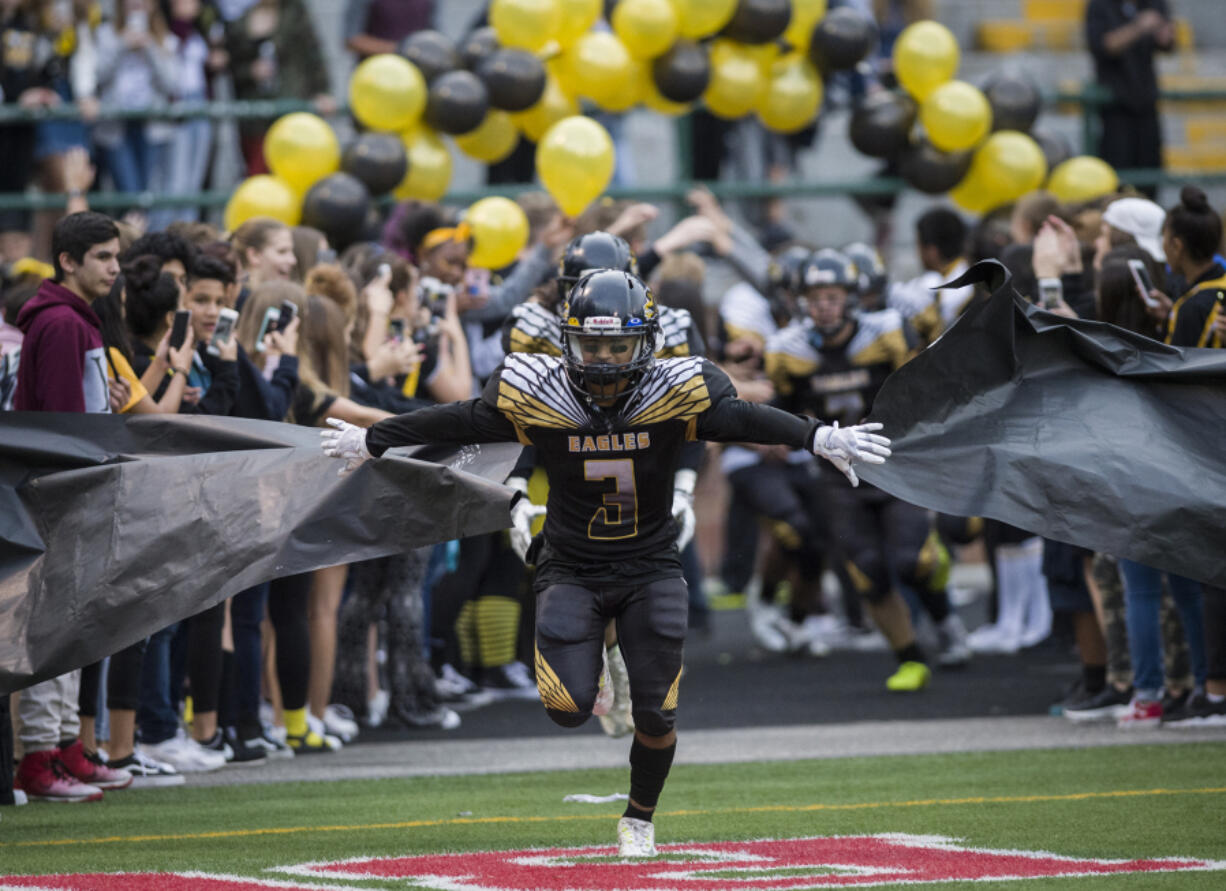 Hudson's Bay's Julio Vara (3) runs through a paper barricade held by Hudson's Bay fans during halftime against Woodland at Kiggins Bowl in Vancouver, Friday Sept. 22, 2017.