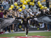 Hudson's Bay's Julio Vara (3) runs through a paper barricade held by Hudson's Bay fans during halftime against Woodland at Kiggins Bowl in Vancouver, Friday Sept. 22, 2017.