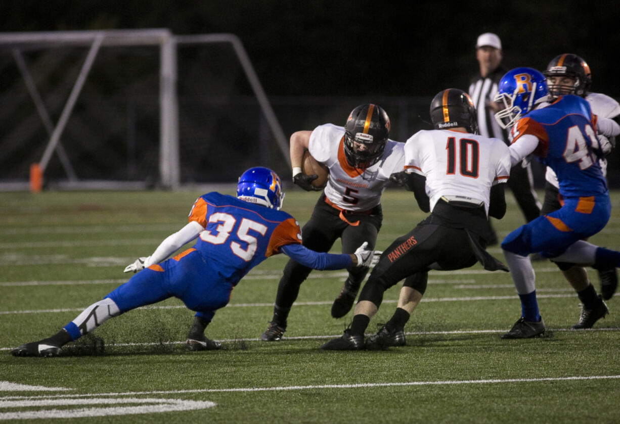 Washougal #5 Kade Coons runs with the ball as Ridgefield High School's Jeremy Martin, #35 tries to tackle him at a game Friday September 29, 2016. Washougal squared off with Ridgefield.