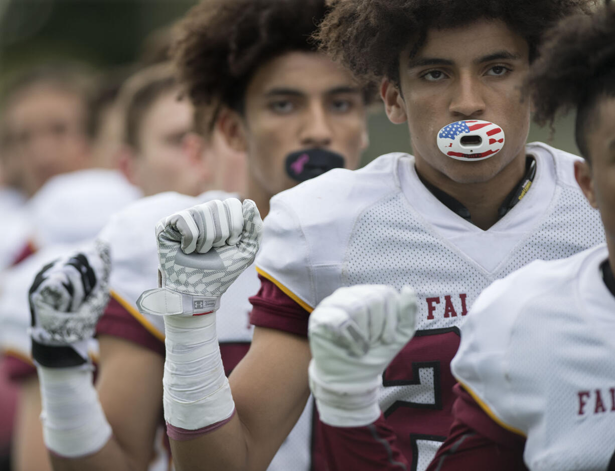 Prairie's Zeke Dixson, background, and AJ Dixson, foreground, raise their fists during the singing of the National Anthem before the game against Evergreen at McKenzie Stadium on Friday afternoon, Sept. 29, 2017.