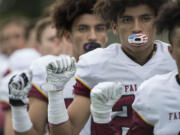 Prairie's Zeke Dixson, background, and AJ Dixson, foreground, raise their fists during the singing of the National Anthem before the game against Evergreen at McKenzie Stadium on Friday afternoon, Sept. 29, 2017.