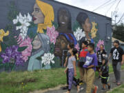 The Albert family, who live near the Fourth Plain corridor, walk past one of the four recently completed wall murals along East Fourth Plain Boulevard on Saturday.