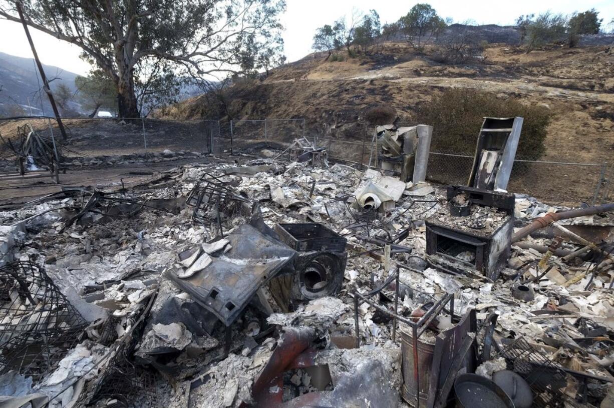 The charred remains of a burned out home are seen Monday, Sept. 4, 2017, in the Sunland-Tujunga section of Los Angeles. Wildfires forced thousands to flee their homes across the U.S. West during a sweltering, smoke-shrouded holiday weekend of record heat. (AP Photo/Ringo H.W.