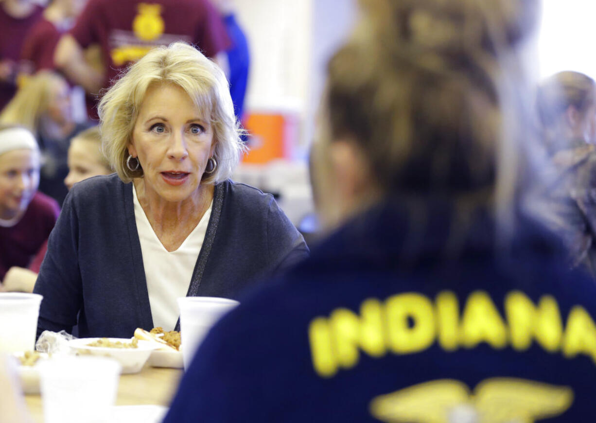 In this Sept. 15, 2017 photo, U.S. Secretary of Education Betsy DeVos talks with Gracie Johnson during a hog roast before a high school football game between Eastern Hancock and Knightstown in Charlottesville, Ind. DeVos uses a private jet to fly around the country to tour schools and attend other work events, the Associated Press has learned.