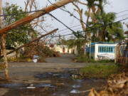 A man and child walk down street strewn with debris and downed power lines in the aftermath of Hurricane Maria, in Yabucoa, Puerto Rico, Tuesday, Sept. 26, 2017.