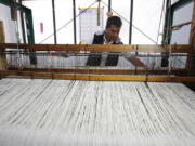 In this Aug., 25, 2017 photo, Carlos Antonio Nino, 57, works in a loom to make ruanas, a traditional Colombian garment, in Nobsa, Colombia. Nino has worked for weeks on a special ruana that he hopes to give to Pope Francis during his upcoming visit to Colombia.