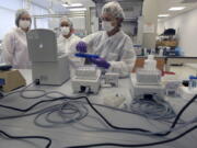 FILE- In this Aug. 10, 2011 file photo Tatyana Gryazeva, right, a criminalist at the Office of Chief Medical Examiner, instructs Lache Rossouw, center, a visiting scientist from South Africa, and Kelsey Baker, an intern, on extracting DNA at a training lab of the New York City Office of Chief Medical Examiner’s Forensic Biology Lab in New York. A technique for analyzing DNA evidence developed by the laboratory has come under fire amid questions about its reliability.