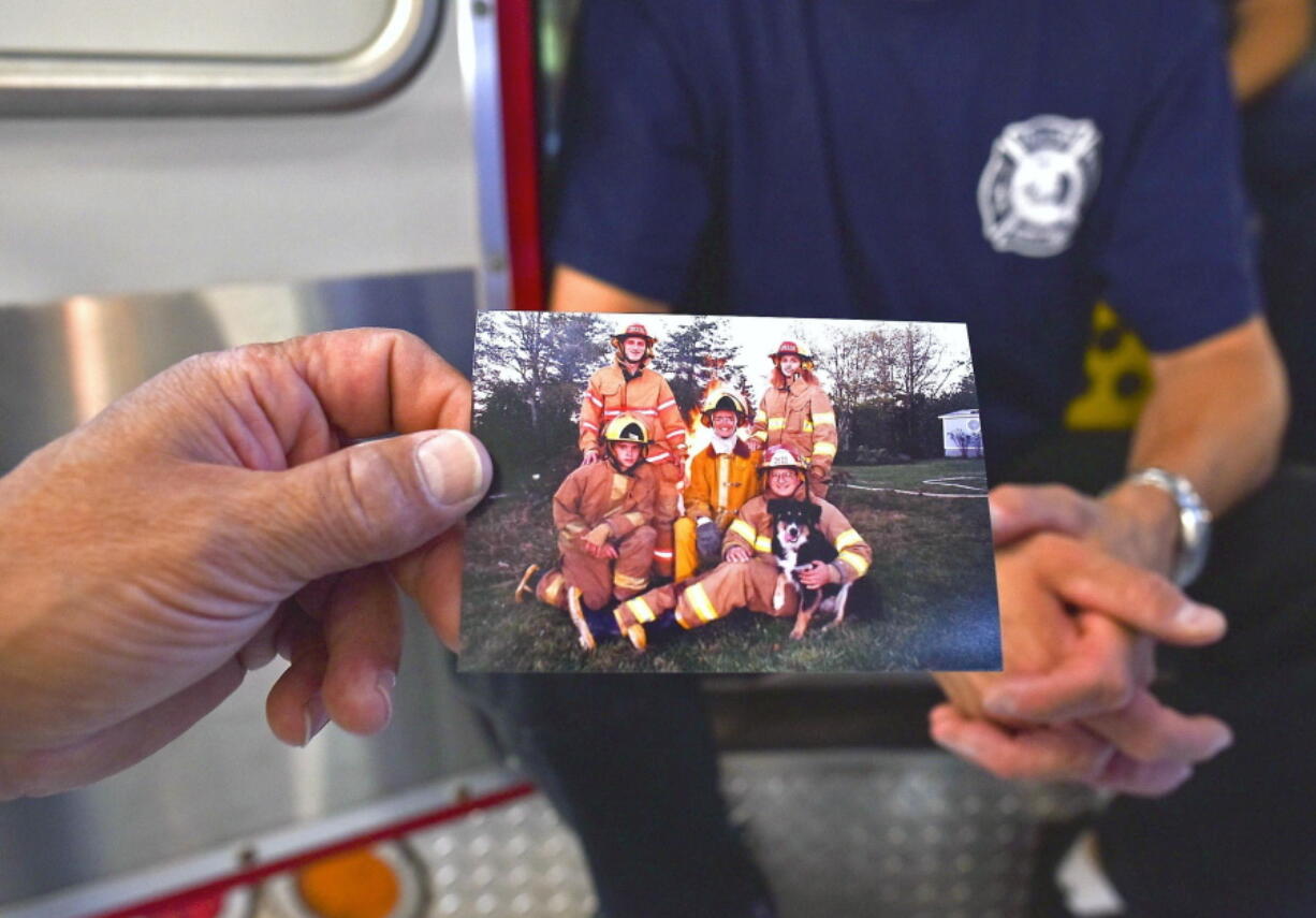 Kevin Miller holds up a photograph showing three generations of the Herndon and Miller family that currently serve in the Lewis and Clark Fire Department near Warrenton, Ore.