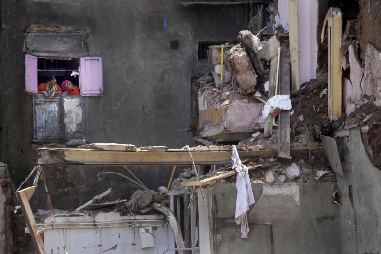 Indian women watch from the window of their house Friday at the collapsed apartment building in Mumbai, India. A five-story building collapsed Thursday in Mumbai where 33 people have died in Indian’s financial capital, after torrential rains lashed western India.