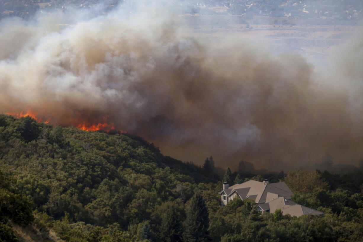 FILE- In this Sept. 5, 2017, file photo, a wildfire burns through residential areas near the mouth of Weber Canyon near Ogden, Utah. Interior Secretary Ryan Zinke is directing all land managers and park superintendents to be more aggressive in cutting down small trees and underbrush to prevent wildfires. In a memo on Tuesday, Sept. 12, Zinke said the Trump administration will take a new approach and work proactively to prevent fires “through aggressive and scientific fuels reduction management” to save lives, homes and wildlife habitat.