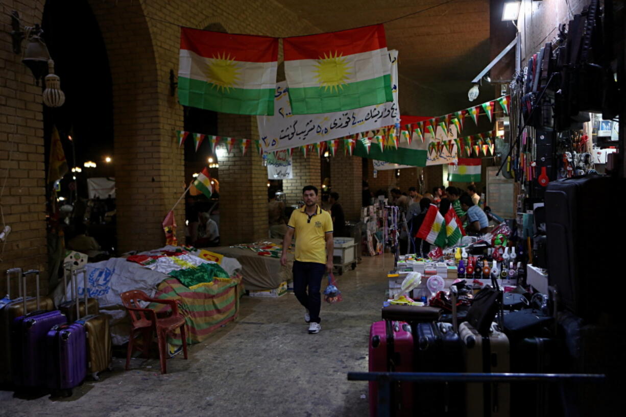 People pass under Kurdish flags. Iraq’s Kurdish region will vote today on a referendum for independence.