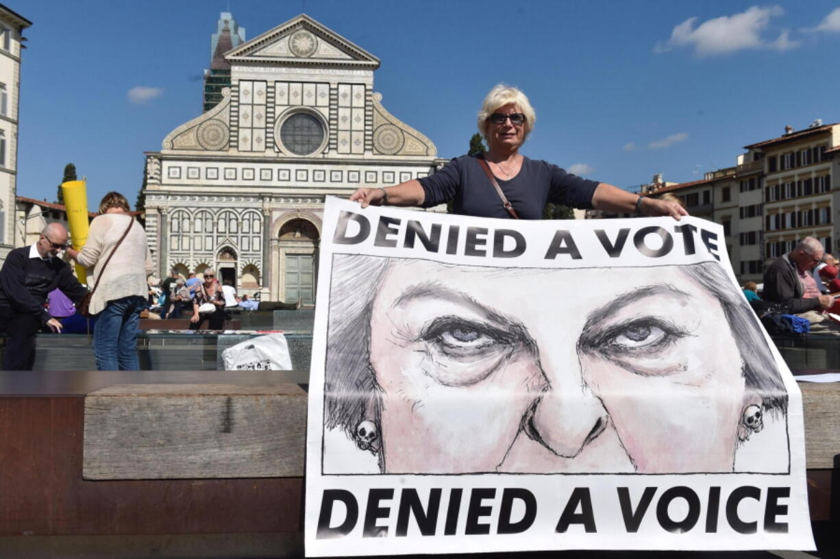 A woman holds a poster showing British Prime Minister Theresa May during a protest staged by a group of UK citizens living in Italy, in Florence, Italy, Friday, Sept. 22, 2017. British Prime Minister Theresa May, who is expected to deliver a speech about Brexit in Florence, will try Friday to revive foundering Brexit talks, and unify her fractious government, by proposing a two-year transition after Britain’s departure from the European Union in 2019 during which the U.K. would continue to pay into the bloc’s coffers.