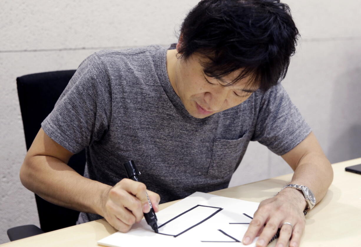 Django Co. Director Shigetaka Kurita writes a pictograph Sept. 14 during an interview at his office in Tokyo. The Japanese creator of the first emoji wanted to add nuance to mobile phone messages and never imagined his work in the late 1990s would become a global phenomenon.