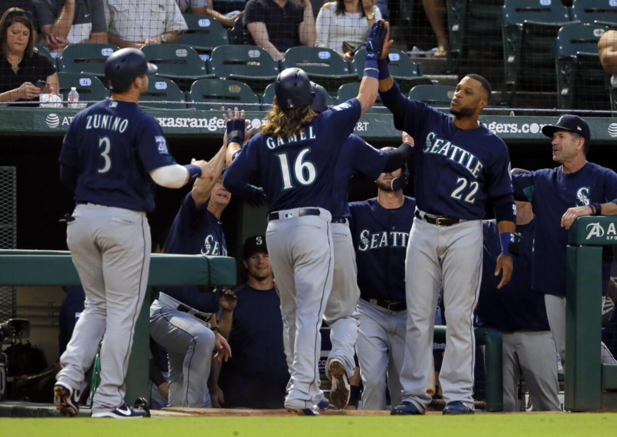 Seattle Mariners’ Ben Gamel (16) is congratulated at the top of the dugout by Robinson Cano (22) after Gamel hit a three-run home run off Texas Rangers’ Miguel Gonzalez that scored Mike Zunino (3) and Yonder Alonso, not seen, during the second inning of a baseball game, Tuesday, Sept. 12, 2017, in Arlington, Texas.