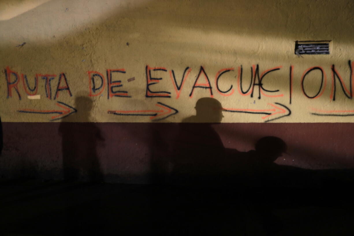 Shadows of rescue workers and volunteers are cast on the wall of an apartment building covered with the spray painted words in Spanish: “Evacuation route” in the southern neighborhood of Tlalpan in Mexico City, on Monday. The 7.1 magnitude quake on Sept. 19 left the complex’s 500 residents, mostly government employees, without a home after one of the 11 buildings collapsed and the others were damaged.