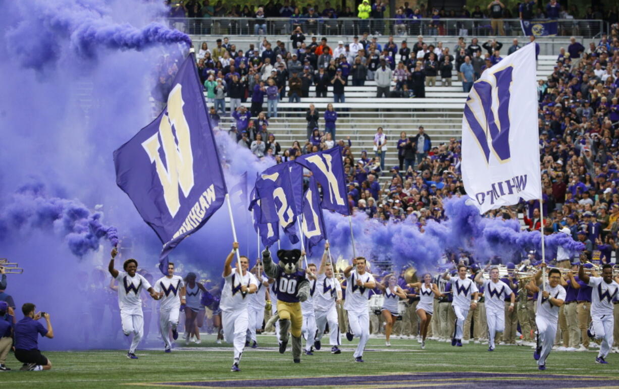 Washington cheerleaders and Harry, the Husky mascot, set off smoke effects as they lead the team out of the tunnel at Husky Stadium for Washington’s home opener, an NCAA college football game against Montana, Saturday, Sept. 9, 2017, in Seattle. (AP Photo/Ted S.