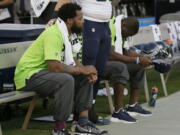 Seattle Seahawks defensive end Michael Bennett, left, sits during the playing of the national anthem next to Justin Britt, center, and another teammate before an NFL preseason football game between the Raiders and the Seattle Seahawks in Oakland, Calif. Bennett is accusing Las Vegas police of racially motivated excessive force when he says he was detained at gunpoint on Aug. 27, 2017, handcuffed and later released without charges following a report that gunshots were heard at a casino hotel.