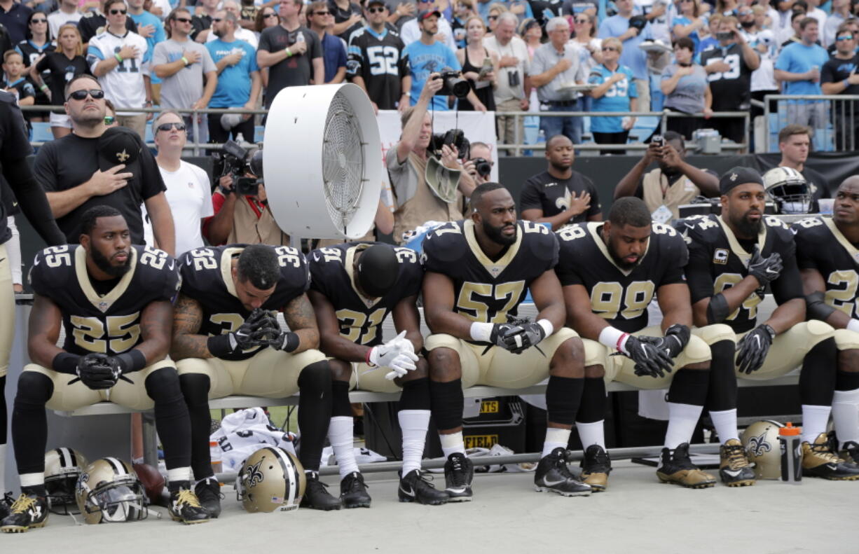 New Orleans Saints players sit on the bench during the national anthem before an NFL football game against the Carolina Panthers in Charlotte, N.C., Sunday, Sept. 24, 2017.