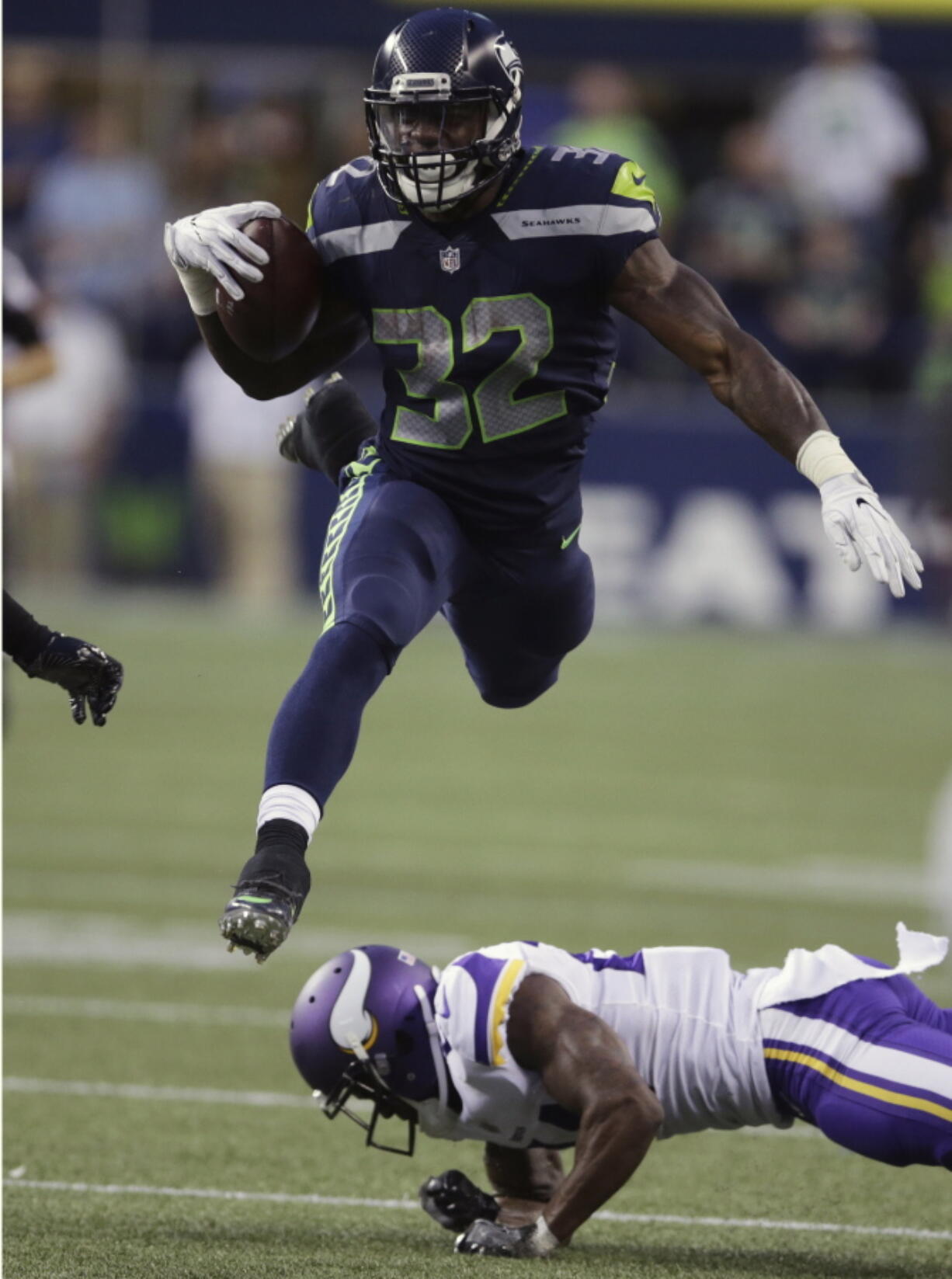 Seahawks running back Chris Carson (32) hurdles Minnesota Vikings cornerback Jabari Price.