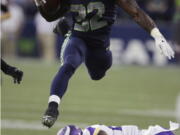 Seahawks running back Chris Carson (32) hurdles Minnesota Vikings cornerback Jabari Price.