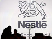 FILE - In this April 7, 2016 file photo Nestle’s directors speak in front of the Nestle’s logo during the general meeting of Nestle Group, in Lausanne, Switzerland. The world’s biggest food and drinks company, Nestle, says it is buying husband-and-wife startup Sweet Earth, which sells frozen burritos stuffed with quinoa, beans and other vegetarian ingredients. The Swiss company, whose frozen food brands include Lean Cuisine and Stouffer’s, said Thursday, Sept.