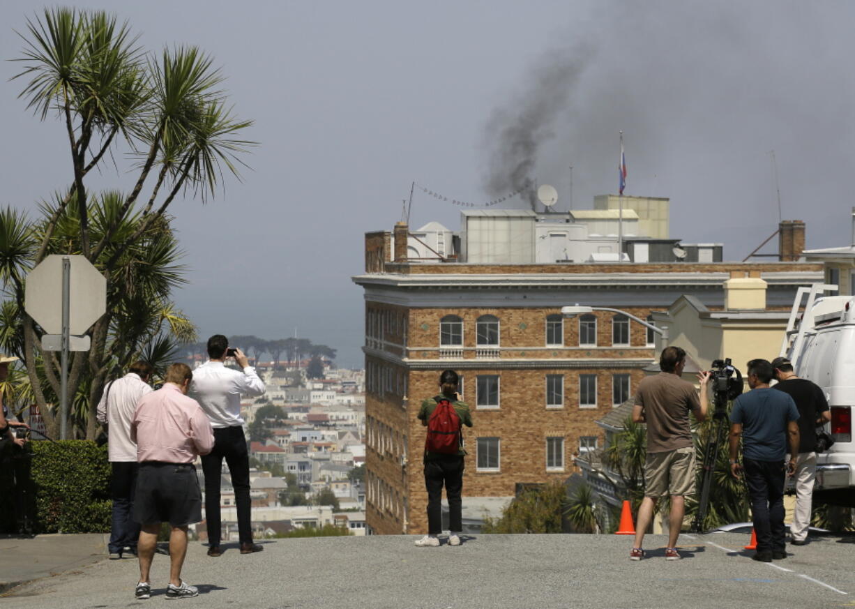 People stop to watch black smoke coming from the roof of the Consulate-General of Russia Friday, Sept. 1, 2017, in San Francisco. The San Francisco Fire Department says acrid, black smoke seen pouring from a chimney at the Russian consulate in San Francisco was apparently from a fire burning in a fireplace. The smoke was seen billowing from the consulate building a day after the Trump administration ordered its closure.