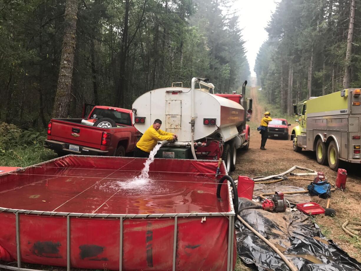 A water tanker driver tops of a folding water tank along a fireline in western Skamania County.