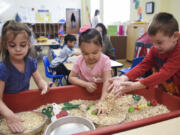 Aaralynn Marua, 4, from left, Alahoni Aguaro-Powell, 4, and Nathan Allan, 5, play with oatmeal in a blended preschool class at Hough Early Learning Center on Friday. About half the class are students with disabilities, while the other half are general education students.