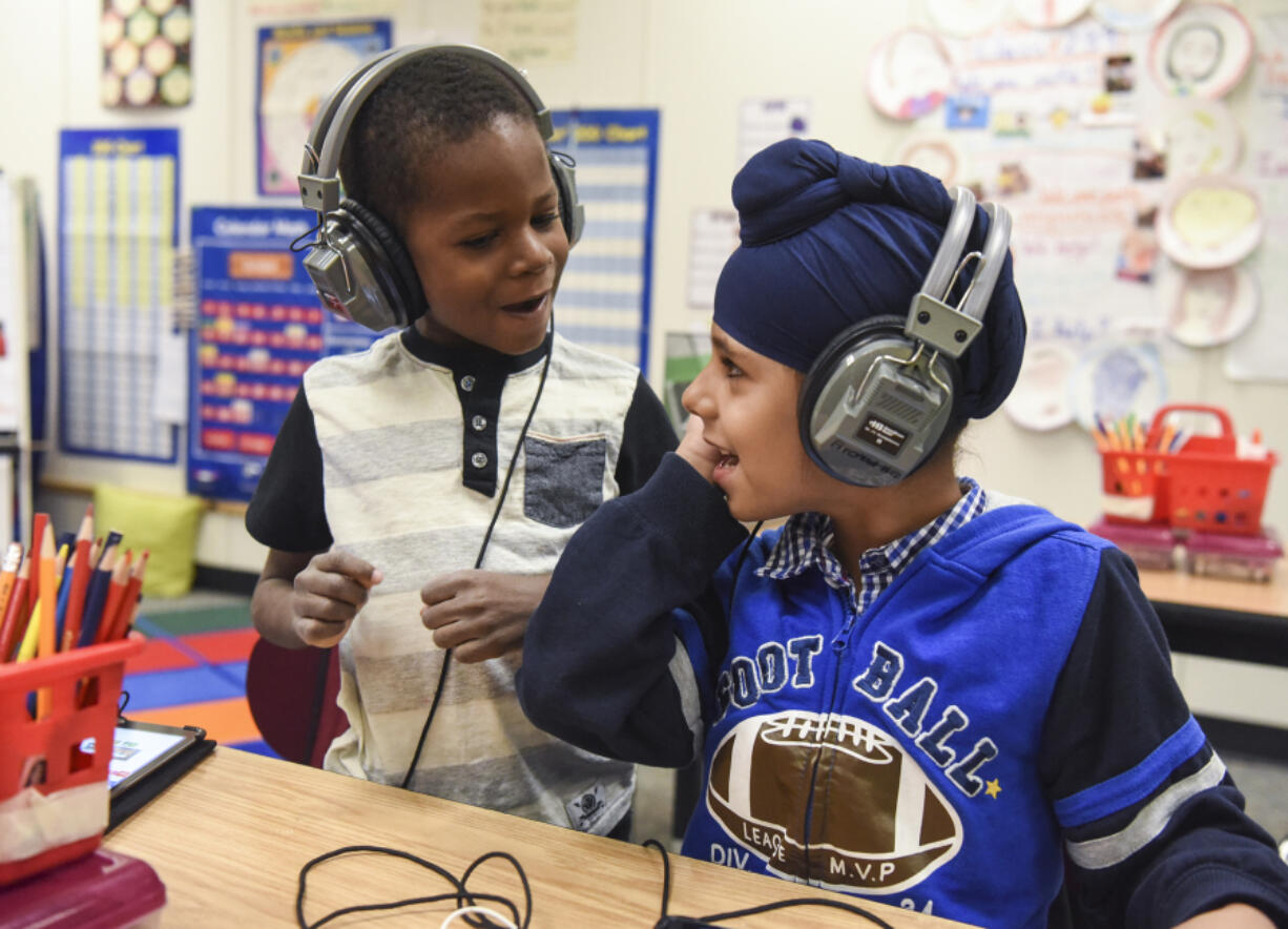 Benaiah Toussaint, 6, from Haiti and Amritpal Singh, 6, from India, sing together while working on iPads in their English language learning class for first through third grades in the Fircrest Elementary School Newcomers Program on Tuesday. Students learn English and about the United States’ culture while enrolled in the program.